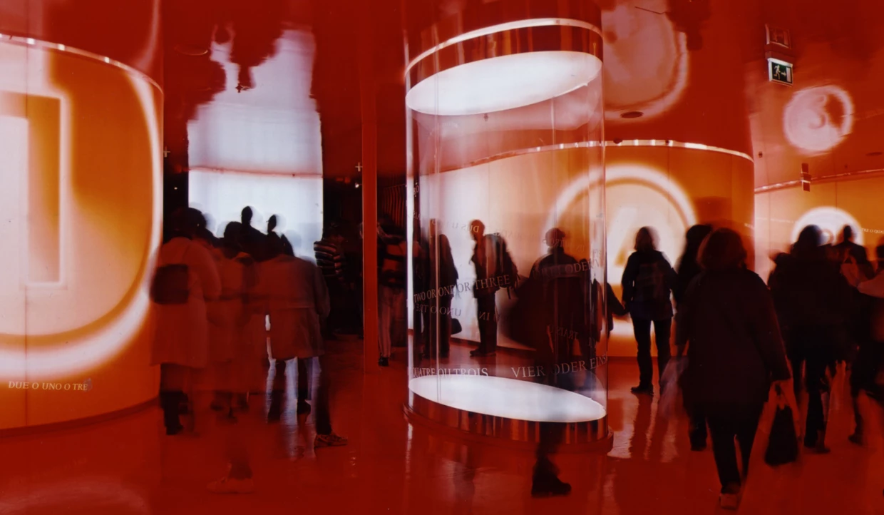 Menschen in einem Raum mit roter Beleuchtung und reflektierenden Oberflächen