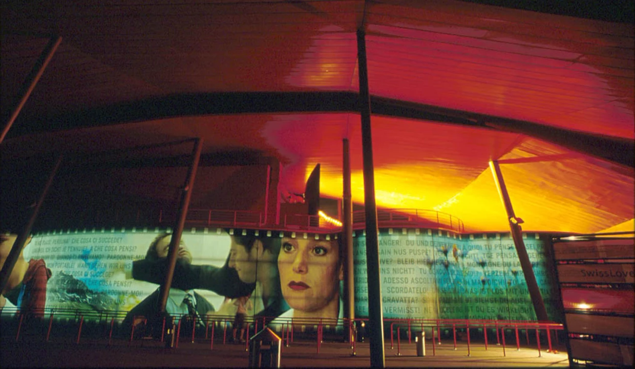 Moderne Fassade mit farbenfrohen Lichtprojektionen und Gesichtern