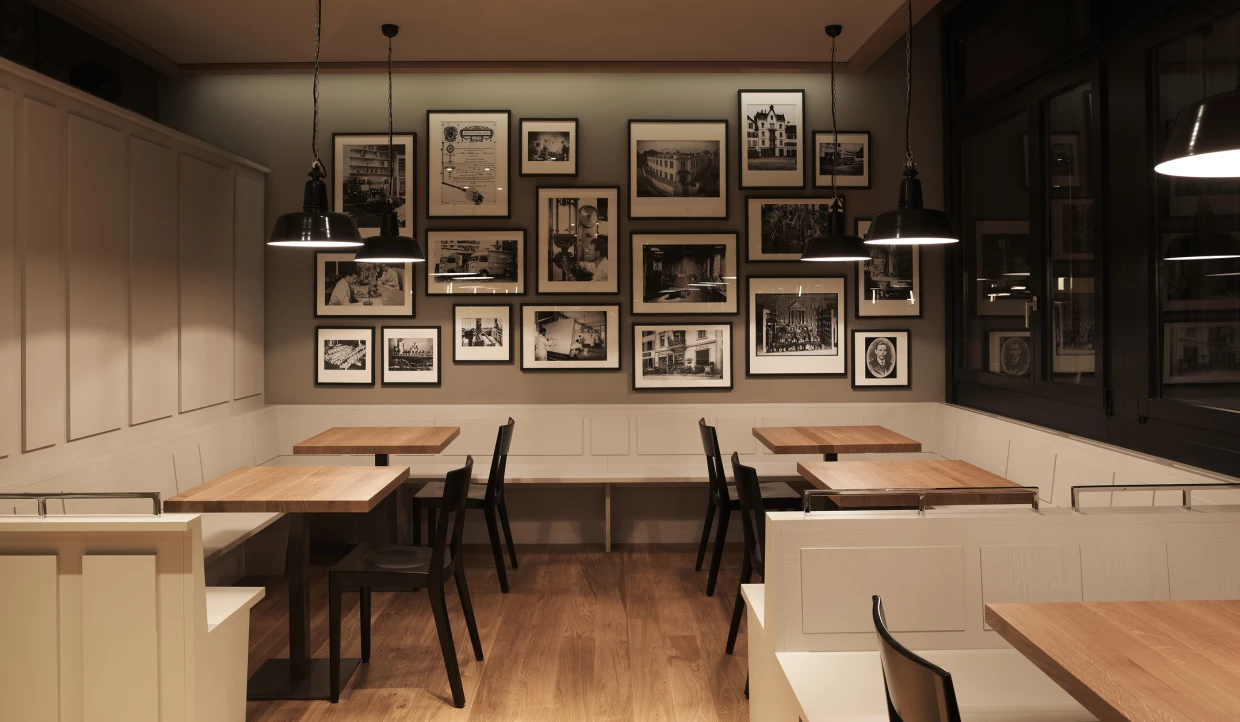 Corner in the restaurant with a photo wall and small wooden tables.