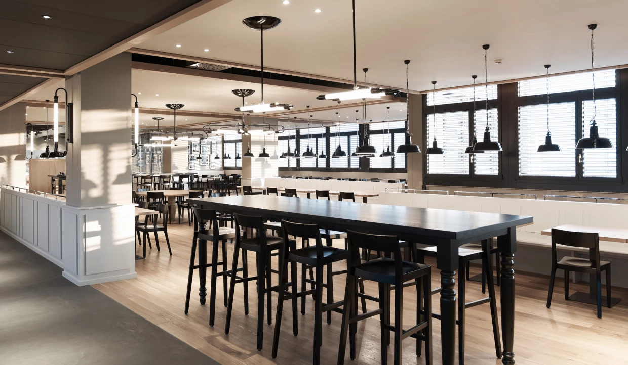 Large restaurant with long tables and many hanging lamps.
