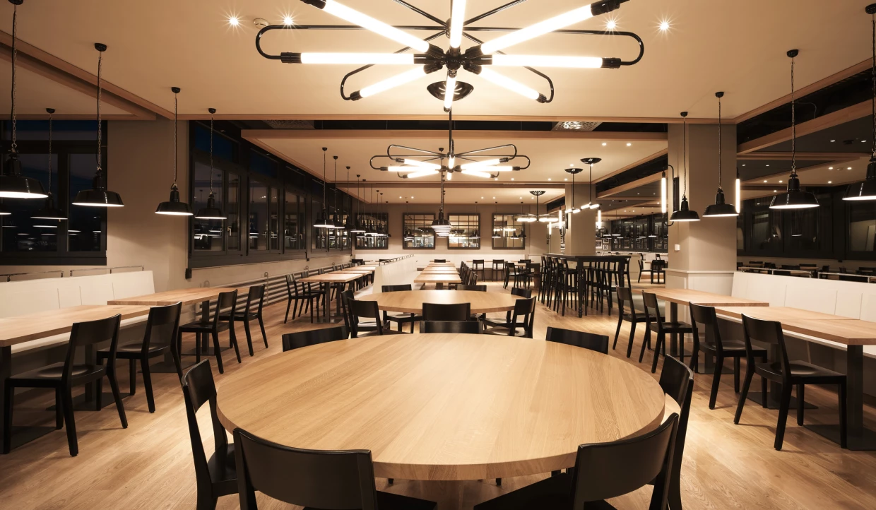 Restaurant at night with illuminated round tables and lamps.