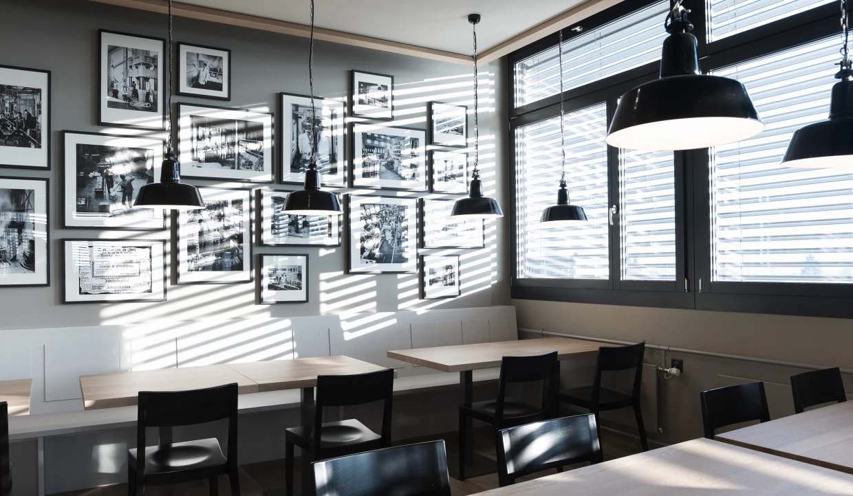 Wall with black-and-white photos and hanging lamps over tables.