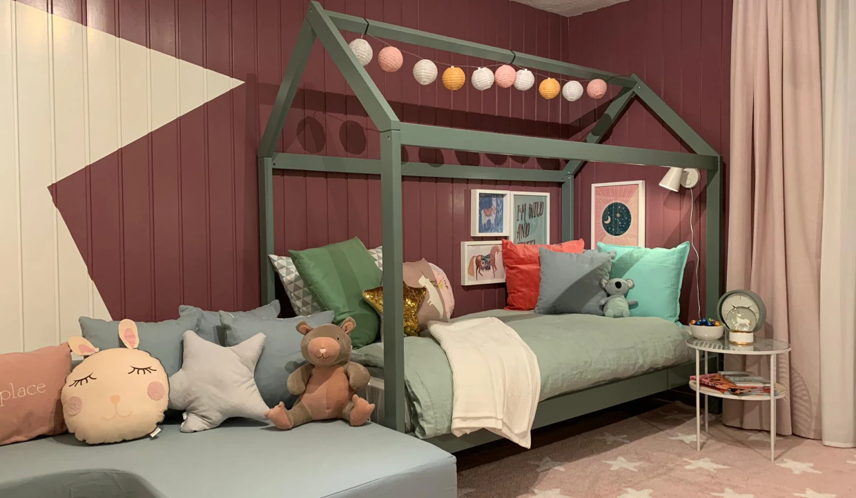 Kinderzimmer mit Hausbett, Kissen und bunter Deko