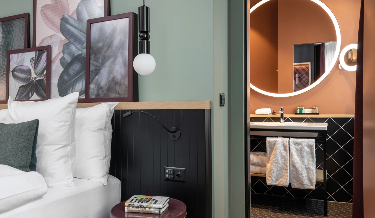 Hotelzimmer-Interior mit Kopfteil, Blick ins Bad, rundem Spiegel, warmen Terracottawänden und diagonalen Fliesen