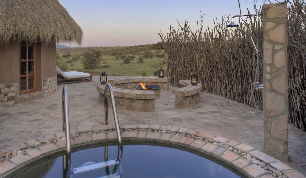 Small pool near a hut with a fire pit.