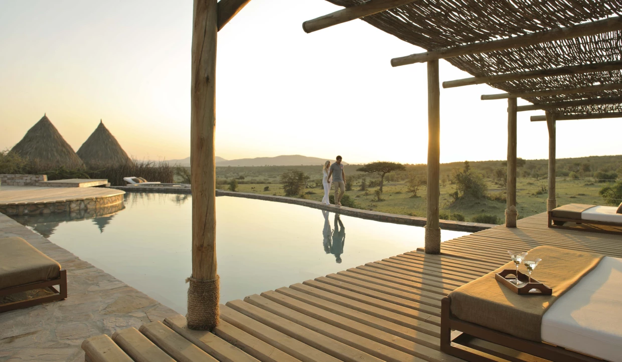 A couple walks by the pool at sunset.