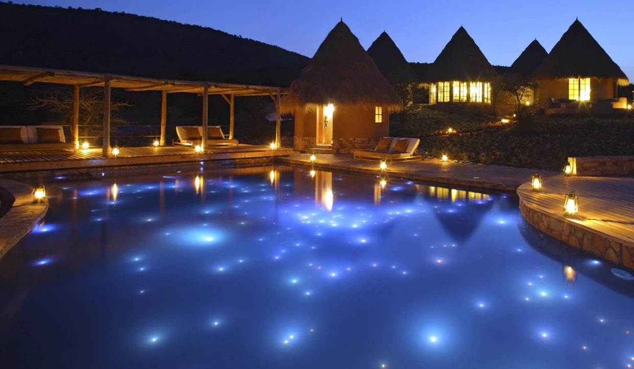 Pool area with lit huts at night.