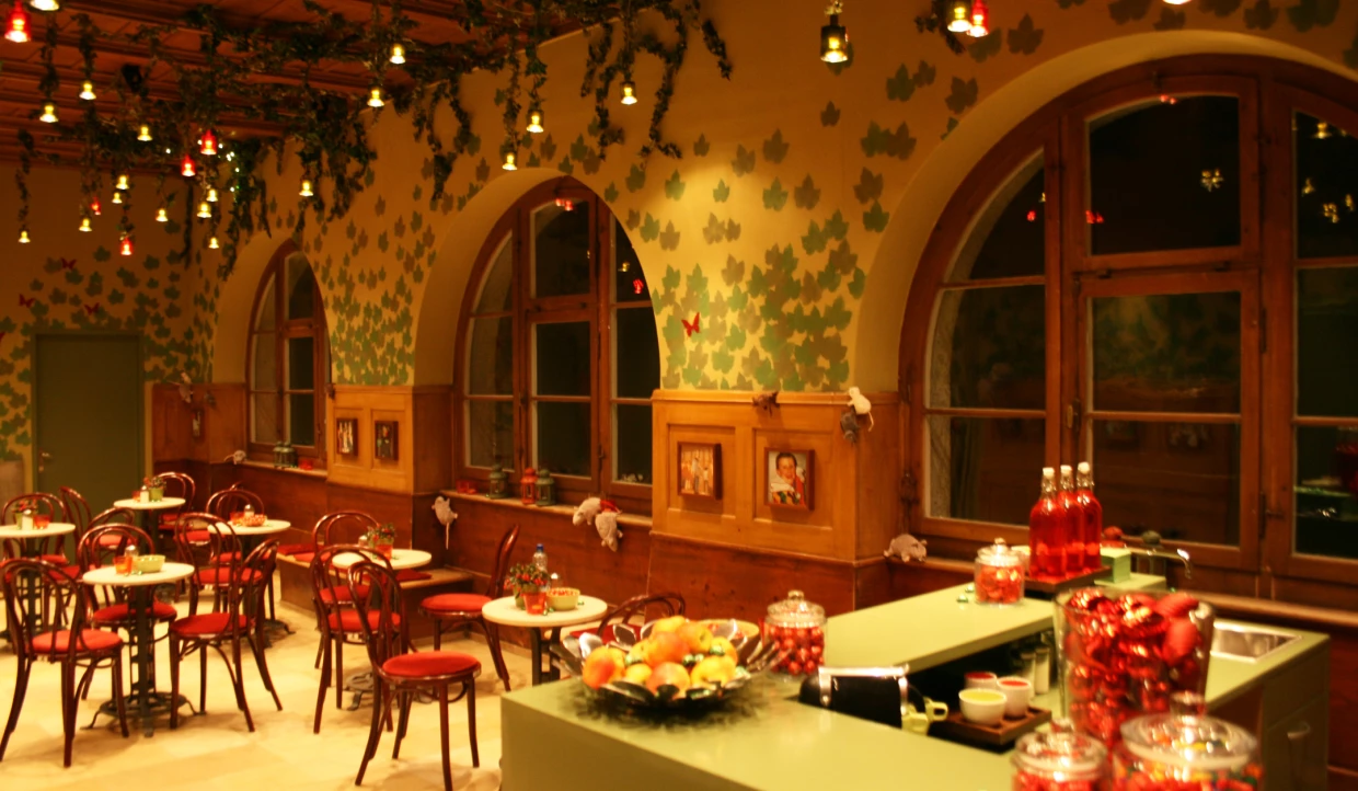 Café mit roten Stühlen, Rundtischen und Laubdekor
