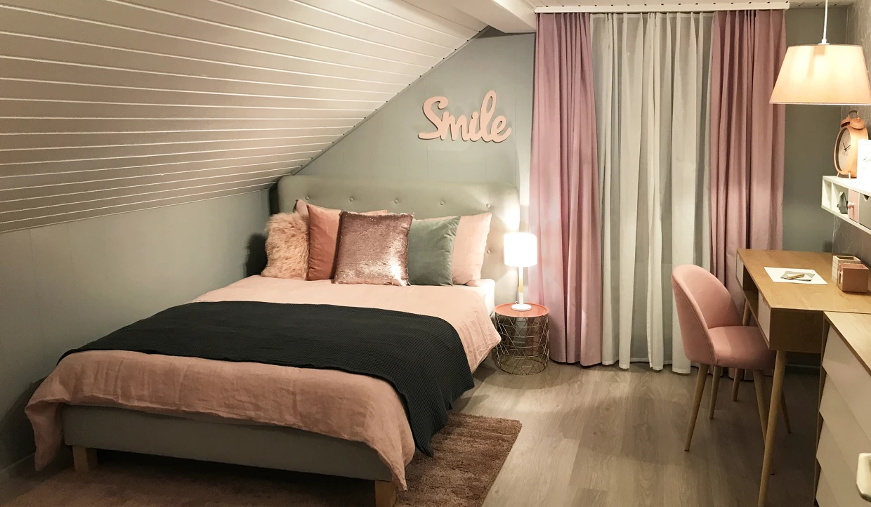 Schlafzimmer mit Bett und Schreibtisch unter Dachschräge