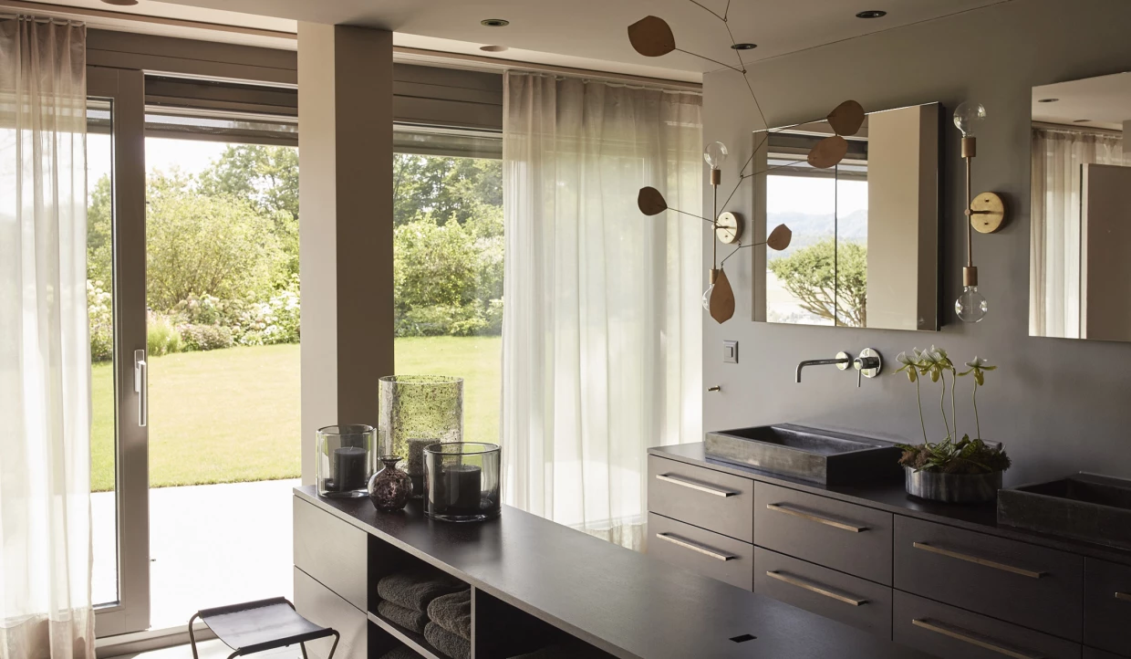 Modernes Badezimmer mit dunklen Möbeln und großem Fenster mit Vorhängen