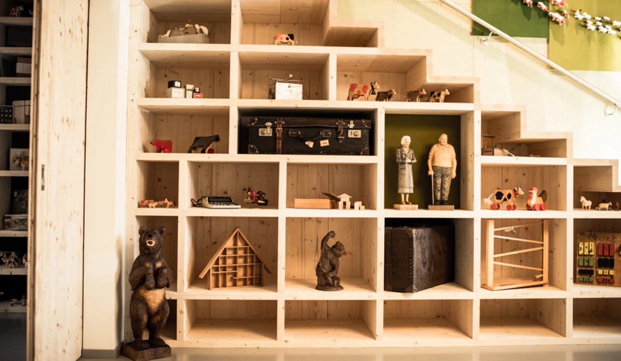 Holzregal mit verschiedenen Figuren und einem Koffer