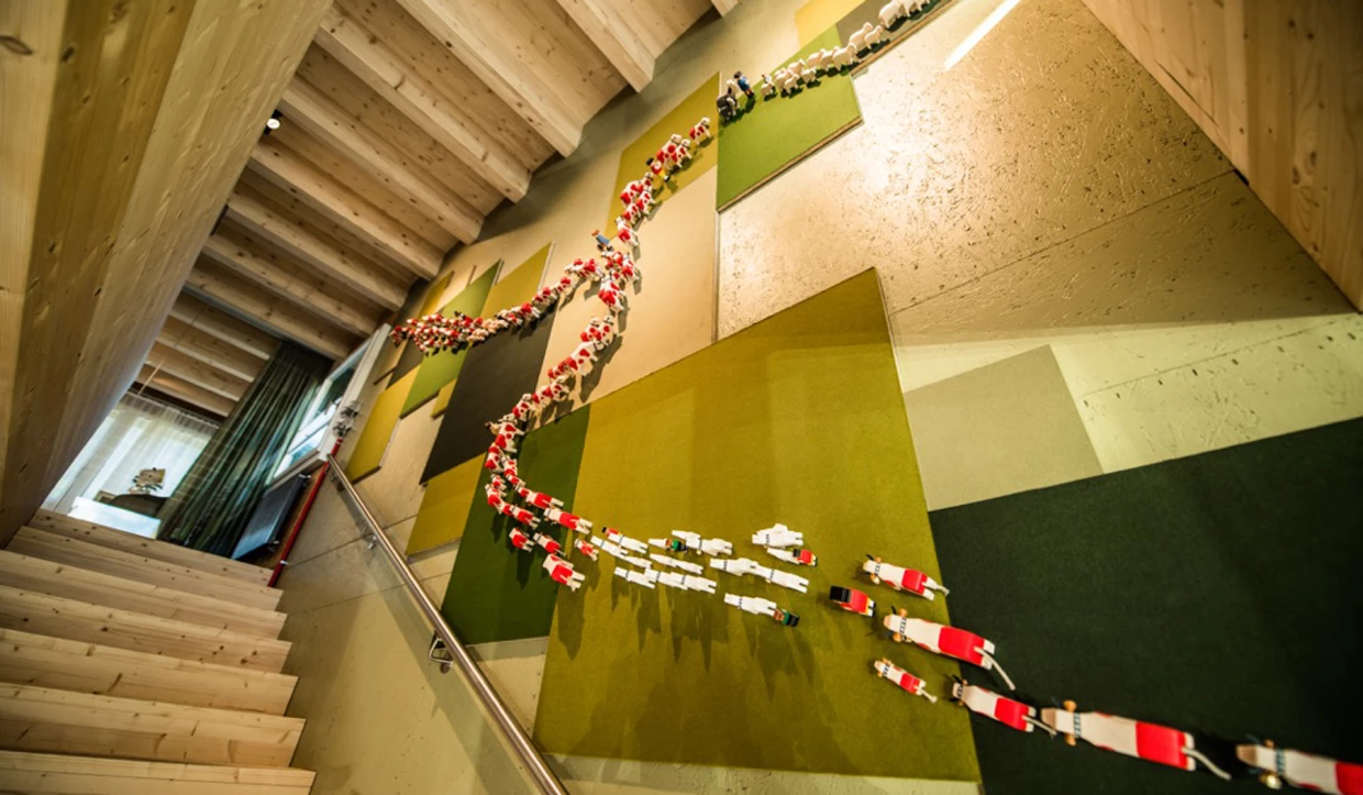 Wanddekoration aus aufgefädelten Kuhfiguren neben Treppe
