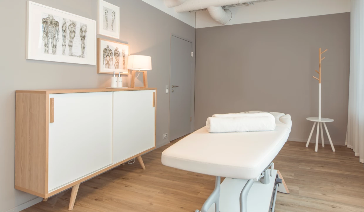 Behandlungsraum mit Liege und anatomischen Bildern