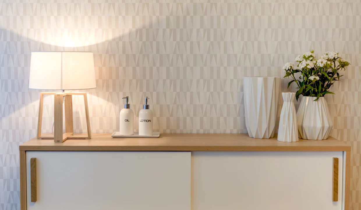 Kommode mit Lampe und dekorativer Vase mit Blumen